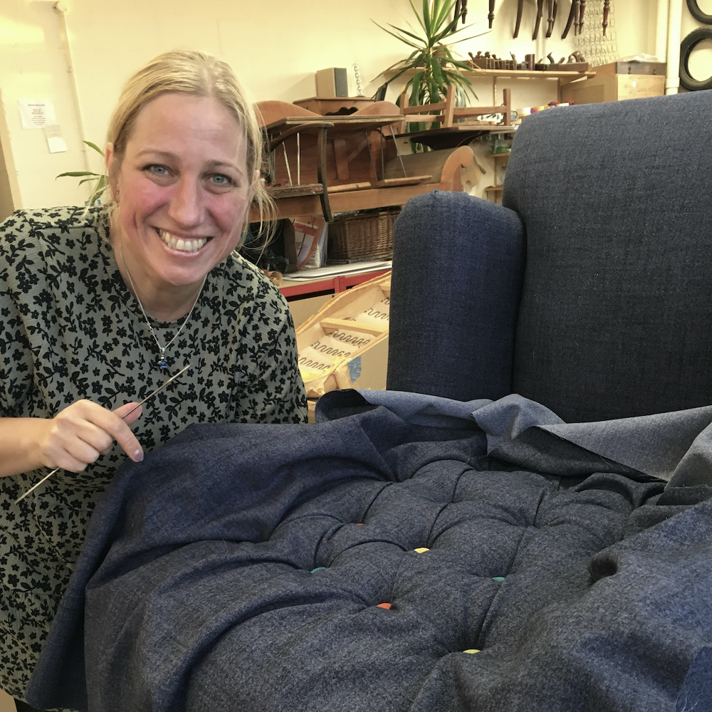 Student creating deep buttoned upholstery on a chair as part of an advanced upholstery technique.